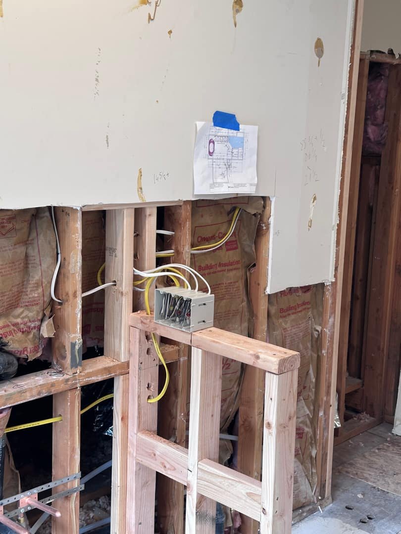 Electrical junction box with visible wiring framed by wooden studs.