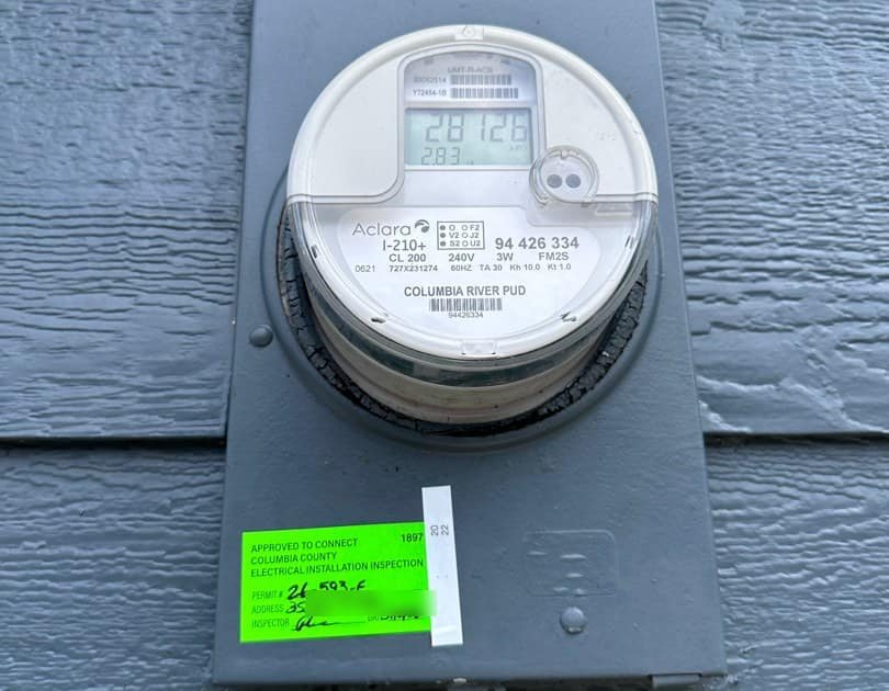 Electric meter with a green 'approved to connect' electrical inspection sticker on the meter base