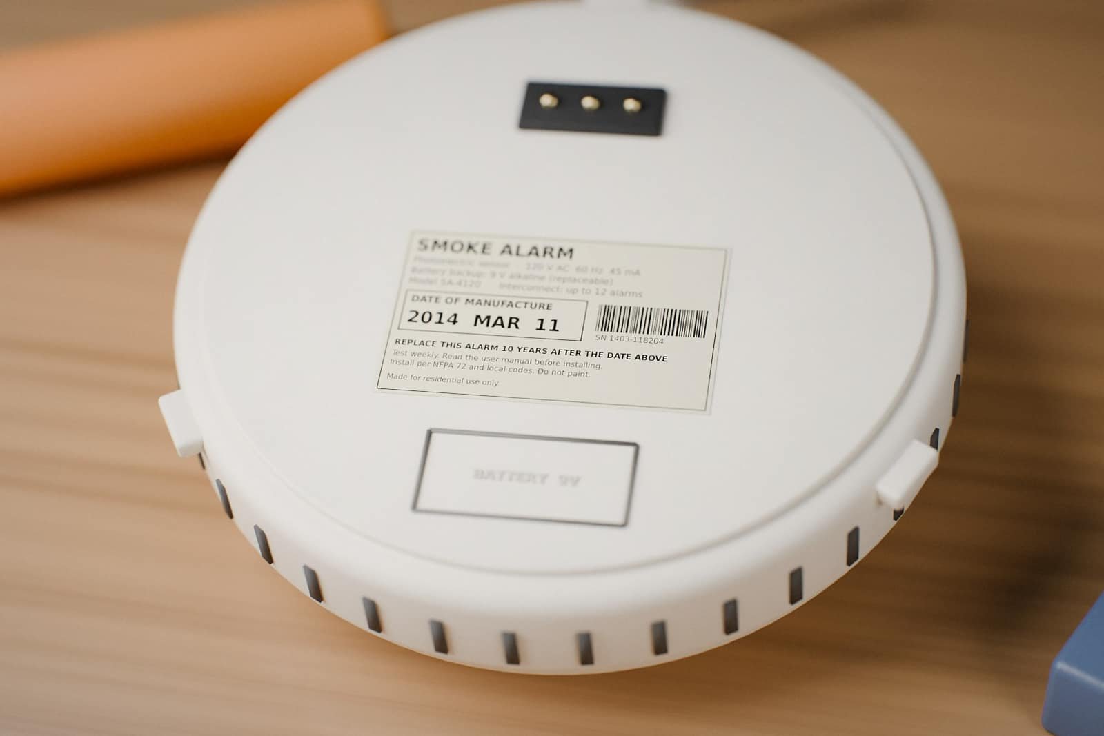 Back of a smoke alarm with a label showing a 2014 date of manufacture, past its 10-year replacement date