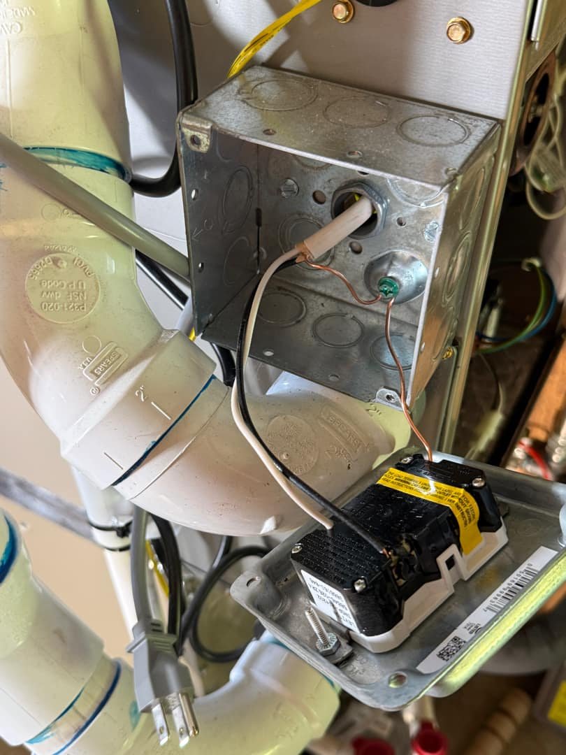 Close-up of a junction box with various wires and conduit in a residential setup.