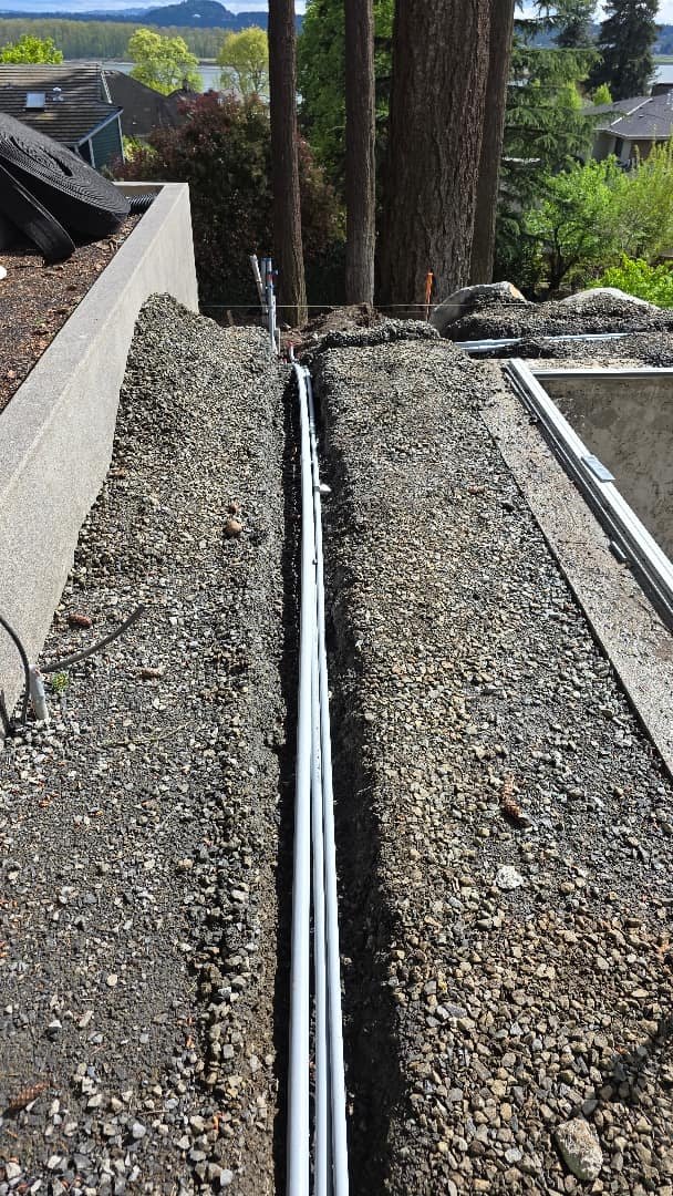 PVC conduit running along a trench on a rooftop, showing the pathway for electrical wiring installation.