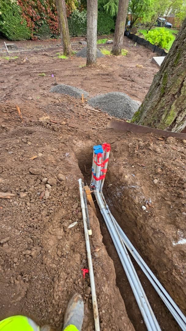 Electrical conduits installed in a trench with a visible pull box for future wiring connections.