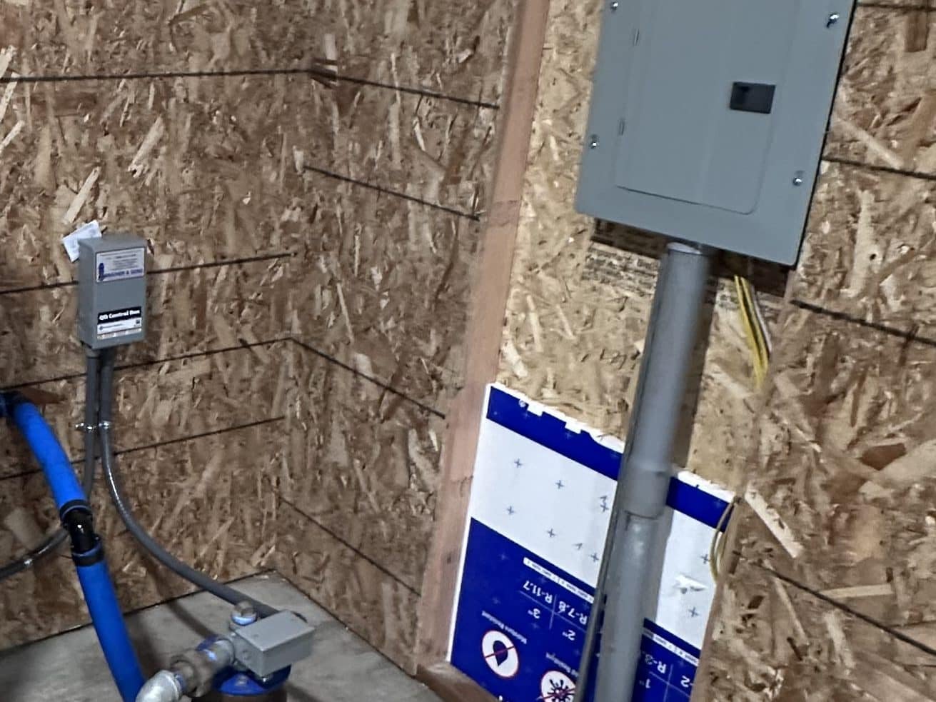 Pump house subpanel fed by underground conduit, with the well pump control box and pressure switch wiring