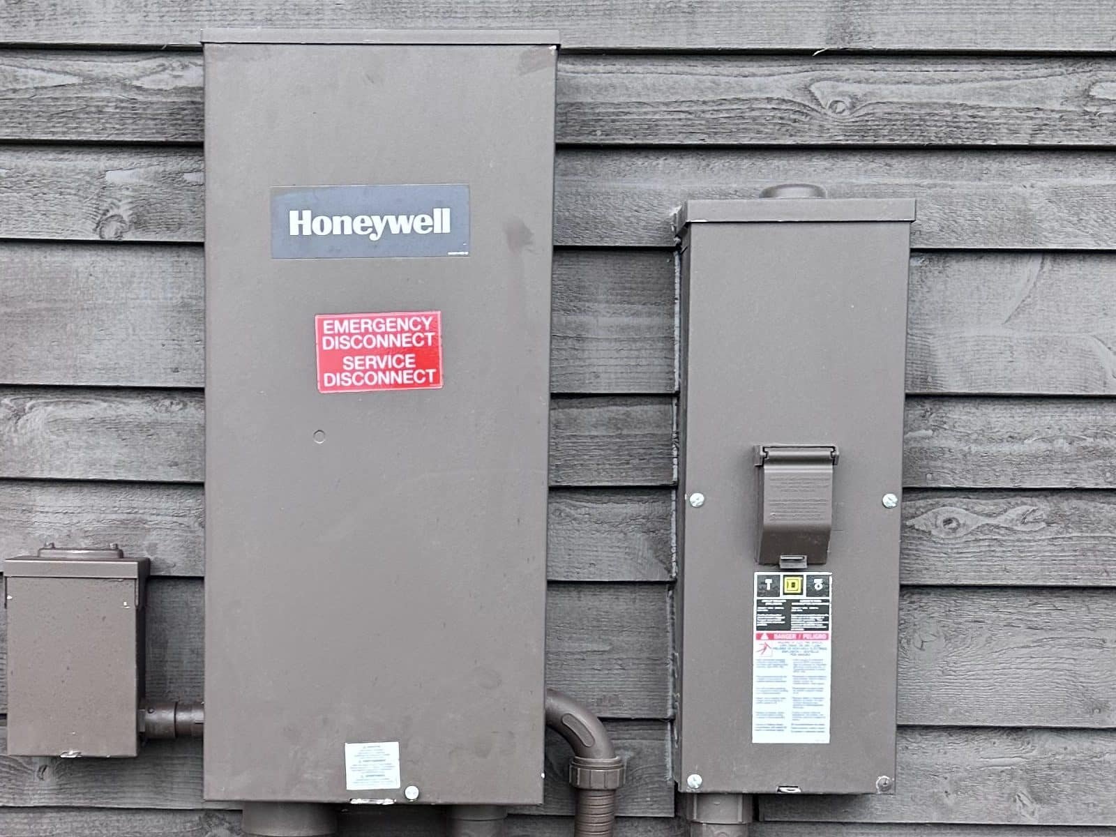 Close-up of the Honeywell automatic transfer switch labeled as the emergency and service disconnect, beside a weatherproof outdoor breaker enclosure
