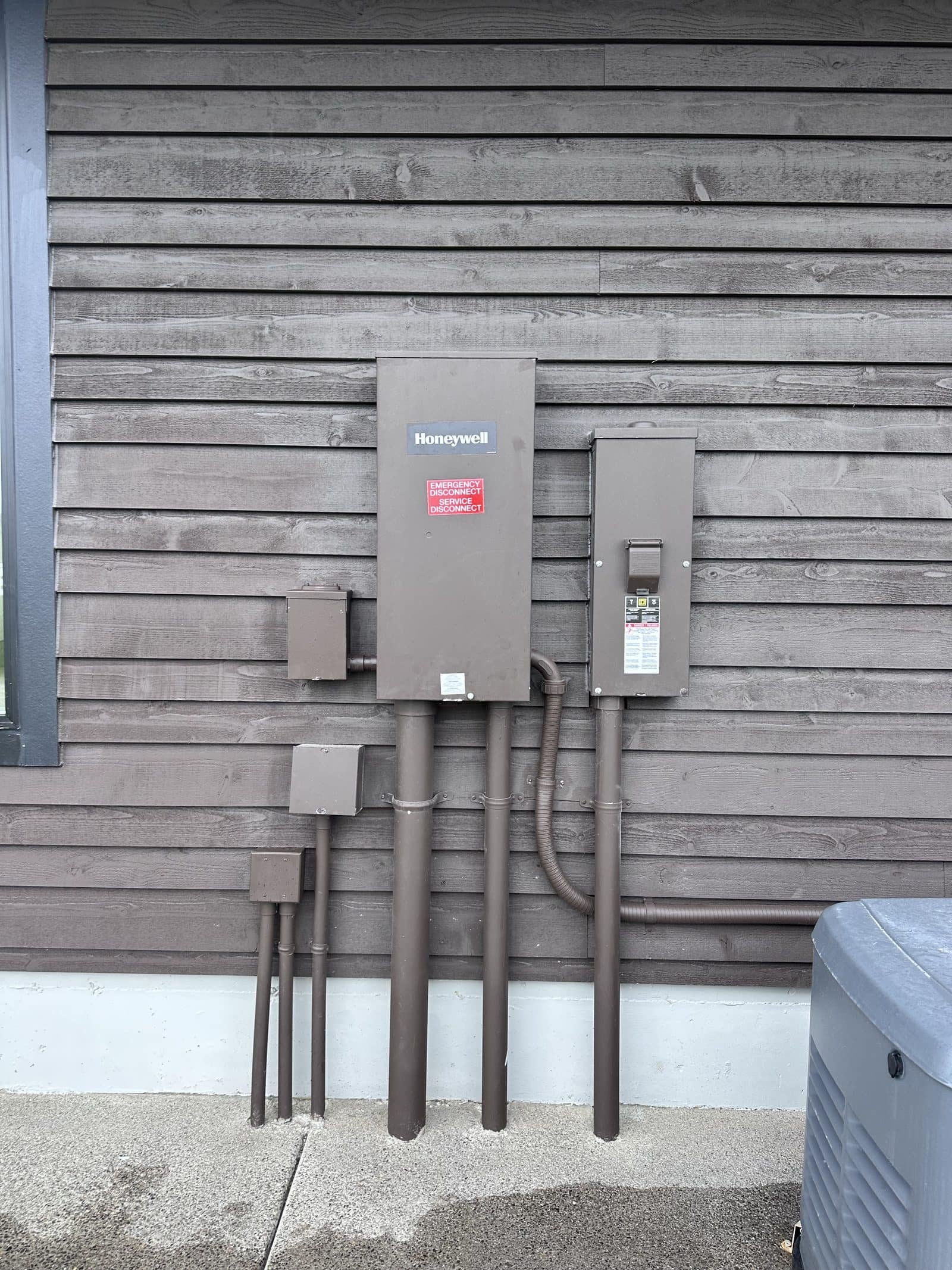 Honeywell service-entrance-rated automatic transfer switch, outdoor breaker enclosure, junction boxes, and underground conduit risers painted to match the house