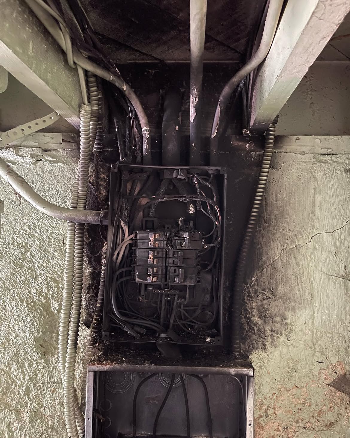 Charred wiring and scorched framing surrounding the failed panel